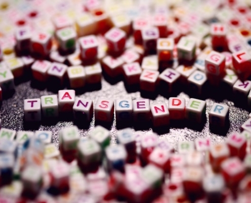 Beads with multicoloured letters on, spelling out the word transgender