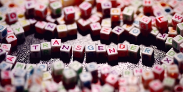 Beads with multicoloured letters on, spelling out the word transgender